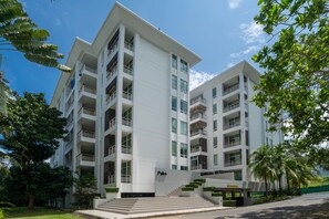 A multi-story building with a flat facade, balconies, and a sign indicating 'Palm' on the ground floor.