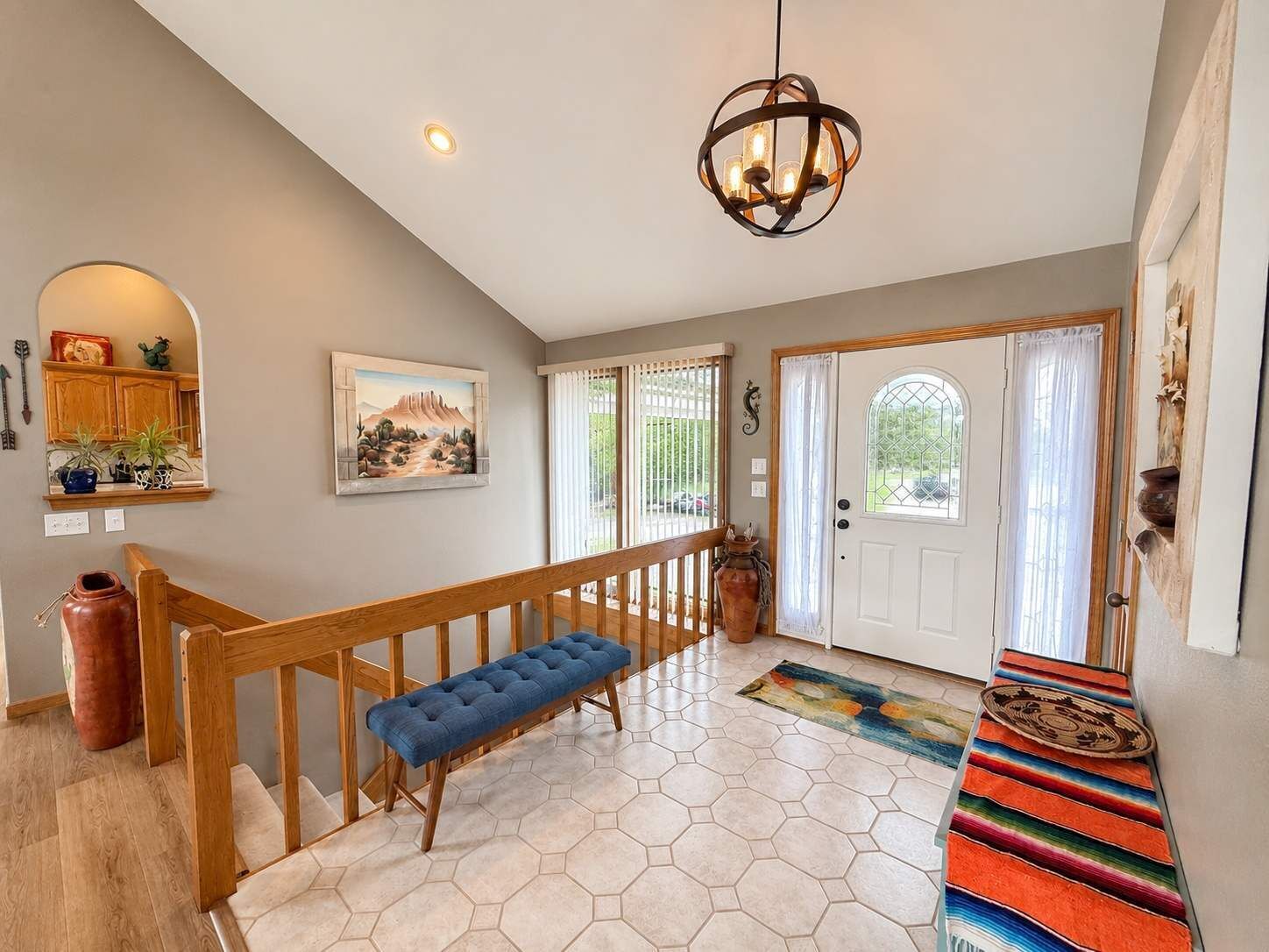 A spacious entryway with a wooden bench, a hexagonal tiled floor, a hanging light fixture, and a door with a window.