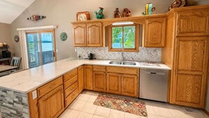 Cocina con gabinetes de madera, salpicadero tipo espiga y un amplio ventanal con vistas al exterior.