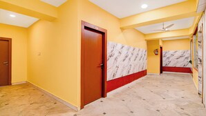Un couloir d’hôtel aux murs jaunes, au sol en marbre et doté d’un ventilateur de plafond.