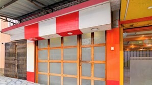 Une façade d’immeuble avec une grande porte centrale et un auvent rouge et blanc.