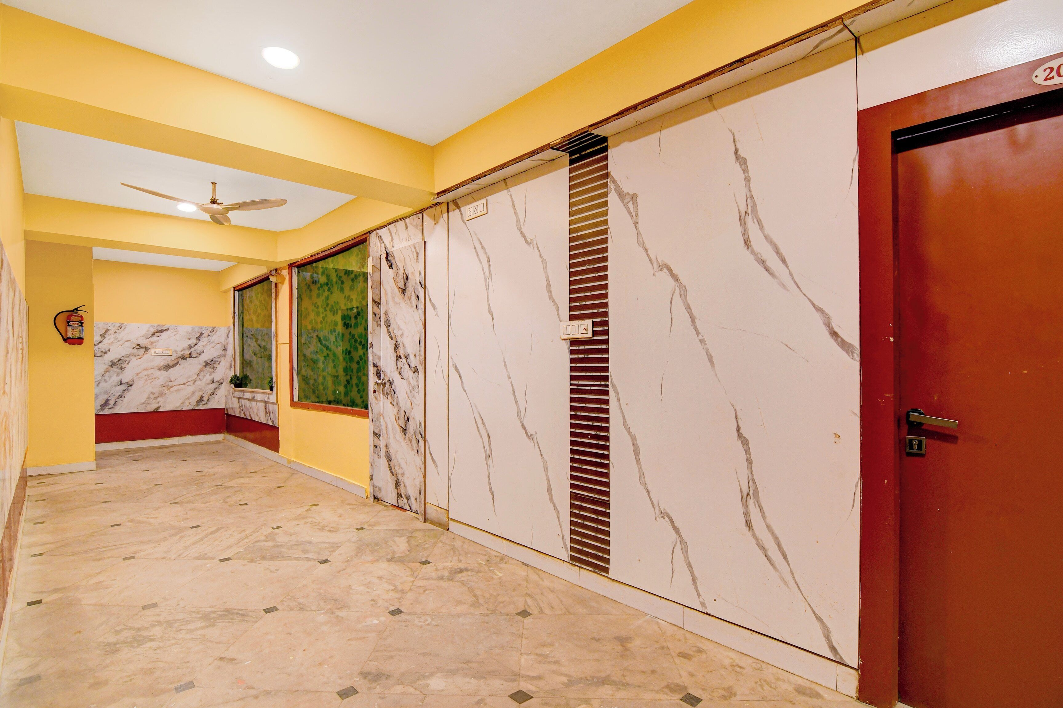 A hallway with yellow walls, a marble floor, and a ceiling fan.