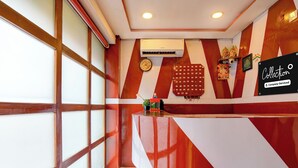 Un espace d’accueil comprenant un comptoir d’enregistrement, une horloge et un climatiseur fixé au mur.