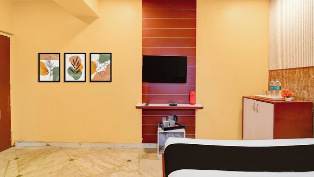 Une chambre d’hôtel équipée d’un lit, d’un téléviseur fixé au mur, d’un petit bureau avec un téléphone et d’une armoire contenant des bouteilles d’eau.
