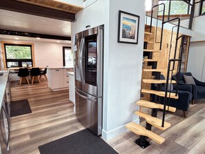 A modern kitchen with a stainless steel refrigerator, wooden flooring, and a dining area with chairs. - Lofted home in a quiet neighborhood of downtown Salida. California king bed plus super comfortable queen murphy bed and FullXL floor mattress in loft. Two levels, two bathrooms, beautifully landscaped private courtyard with hot tub and gas fire pit. (Salida)