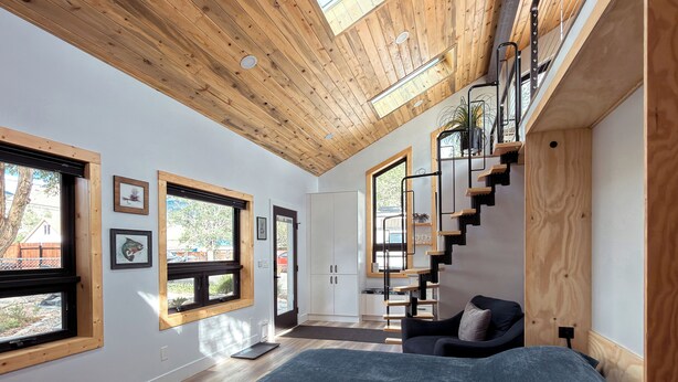 A modern interior with a wooden ceiling, a staircase, a bed, and a view of the outdoors. - Lofted home in a quiet neighborhood of downtown Salida. California king bed plus super comfortable queen murphy bed and FullXL floor mattress in loft. Two levels, two bathrooms, beautifully landscaped private courtyard with hot tub and gas fire pit. (Salida)