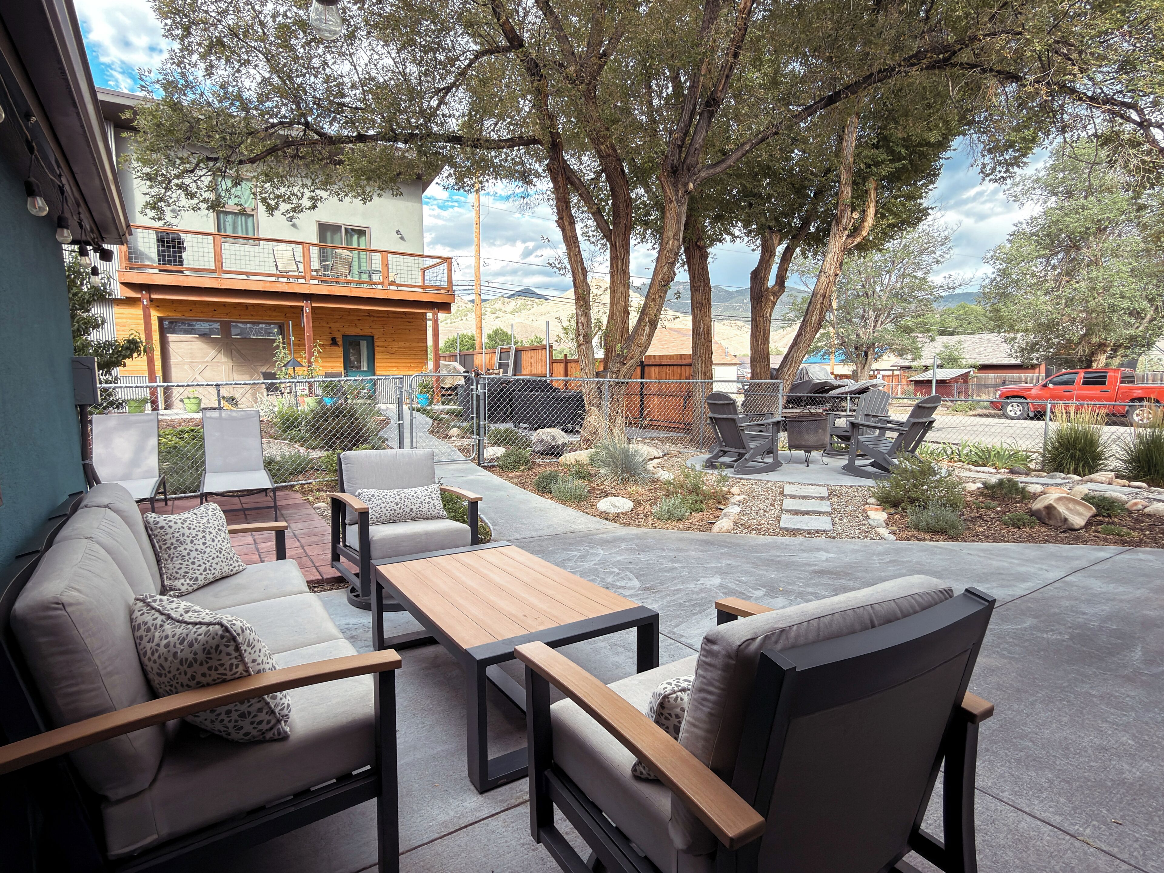 An outdoor patio with seating, a barbecue area, and a view of a building and trees.