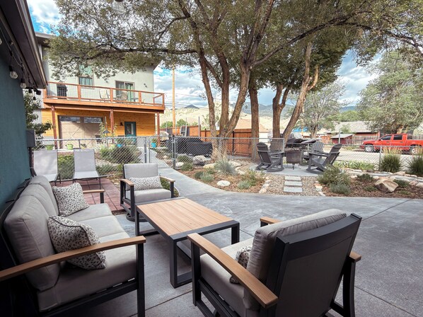 An outdoor patio with seating, a barbecue area, and a view of a building and trees. - Lofted home in a quiet neighborhood of downtown Salida. California king bed plus super comfortable queen murphy bed and FullXL floor mattress in loft. Two levels, two bathrooms, beautifully landscaped private courtyard with hot tub and gas fire pit. (Salida)