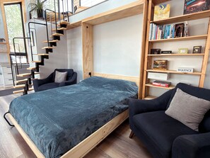 A modern bedroom with a bed, a sofa, a bookshelf, and a staircase. - Lofted home in a quiet neighborhood of downtown Salida. California king bed plus super comfortable queen murphy bed and FullXL floor mattress in loft. Two levels, two bathrooms, beautifully landscaped private courtyard with hot tub and gas fire pit. (Salida)
