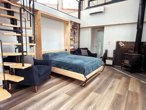 Ein Schlafzimmer im Loft-Stil mit einem Bett, einem Sessel, einem Bücherregal und einem Kamin.