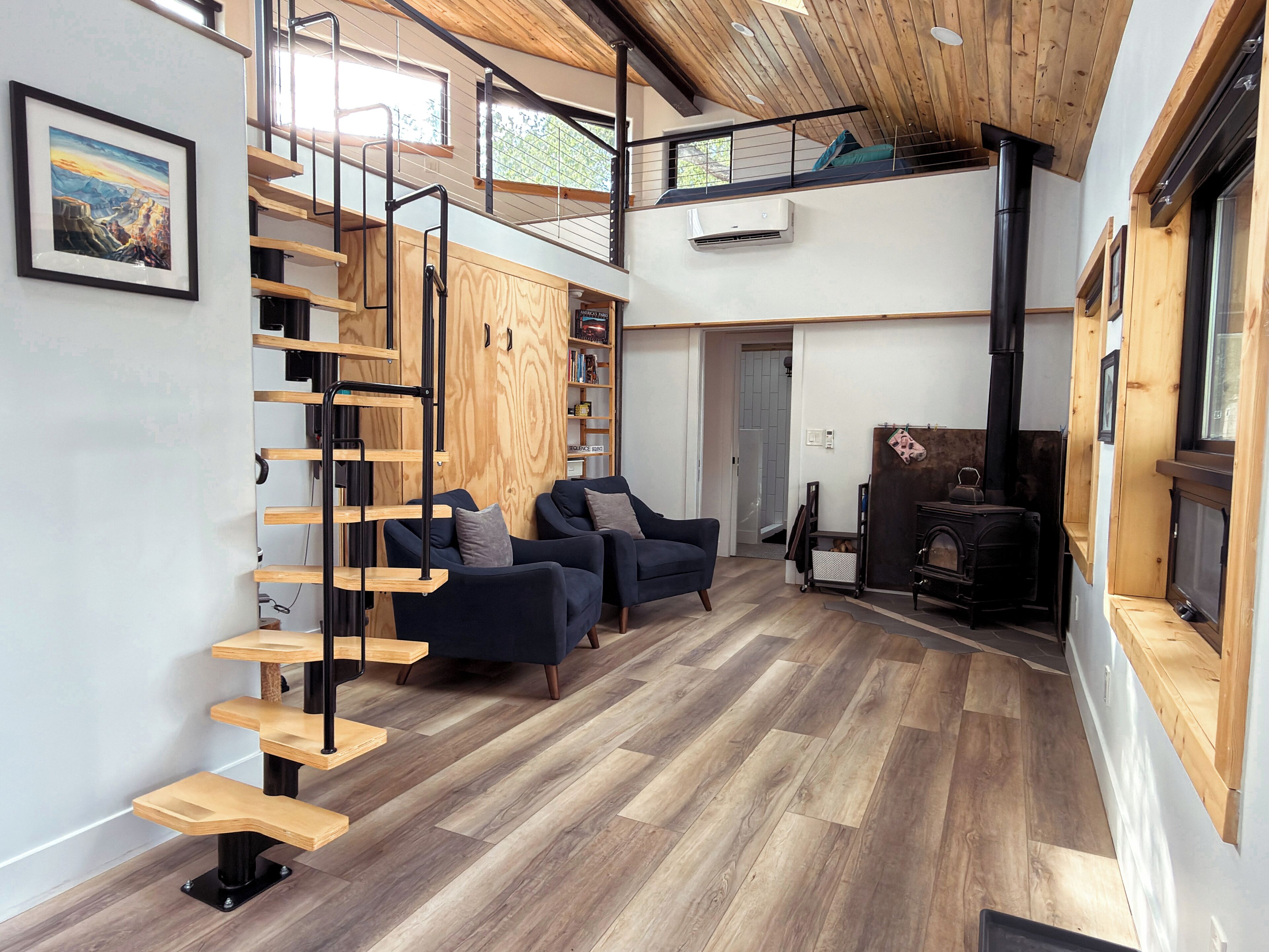 A spacious loft with a wooden staircase, a fireplace, and a mezzanine level.