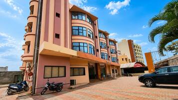 A multi-story building with a curved facade, a covered entrance, and a paved driveway.