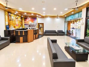 A hotel lobby with a reception desk, seating area, and a mural on the wall. - Hotel Sukh Sagar (Veraval)