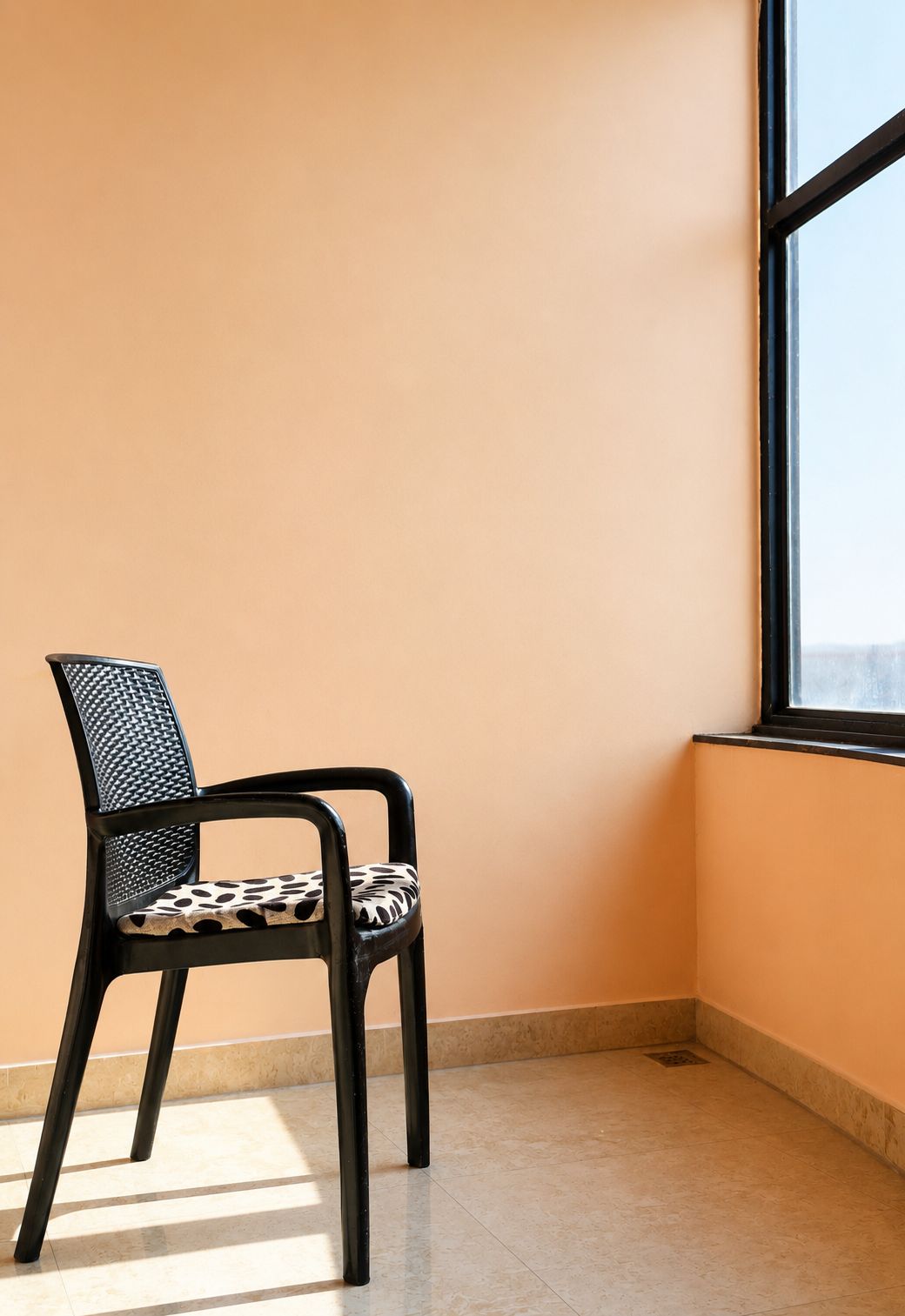 A chair with a patterned seat and backrest, positioned next to a window with a view.