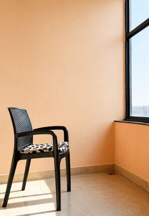 A chair with a patterned seat and backrest, positioned next to a window with a view.