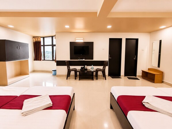 A hotel room with two beds, a desk, a television, and a wardrobe.