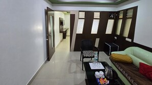 Une chambre d’hôtel comprenant un coin repas, un canapé, un fauteuil et une table avec une bouteille d’eau et des verres.