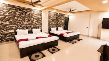Habitación de hotel con dos camas, televisión de pantalla plana, ventiladores de techo y pared con diseño.