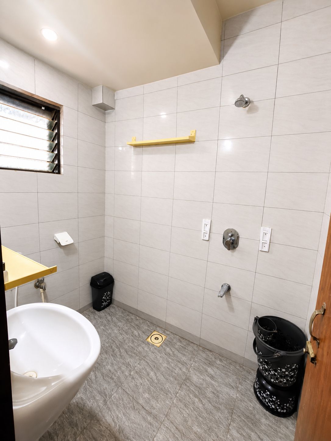 Un baño con inodoro, lavamanos, ducha y un cubo de basura.