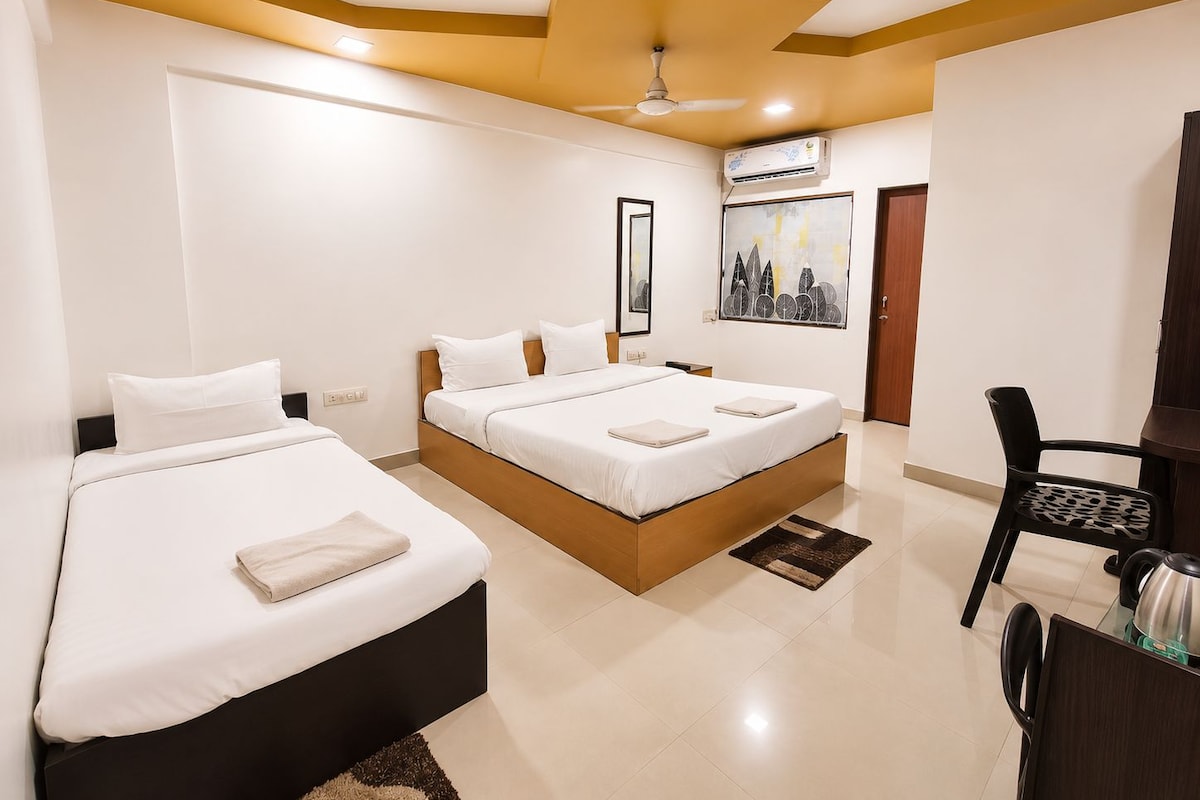 A hotel room with two beds, a ceiling fan, an air conditioning unit, a desk with a chair, and a painting on the wall.