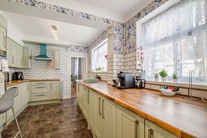 Una cocina con paredes de ladrillo blanco, encimera de madera y una ventana con cortinas florales.