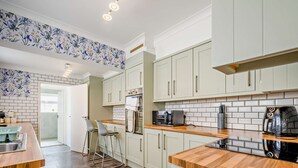 Eine moderne Küche mit weißen Schränken, einer Holz Arbeitsplatte und einem Edelstahl-Spülbecken.
