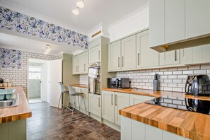 Eine moderne Küche mit weißen Schränken, einer Holz Arbeitsplatte und einem Edelstahl-Spülbecken.