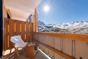 A wooden balcony with a white chair and a small table, overlooking a snowy mountain range. - Residence Les Olympiades, Ski In-Out with WiFi in Val Thorens, “V5” by Versant Collection (Val Thorens)