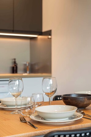 A dining table set with clear glassware, plates, and a bowl, with a modern kitchen in the background. - Residence Dôme de Polset, Ski In-Out with WiFi in Val Thorens, “V13” by Versant Collection (Val Thorens)