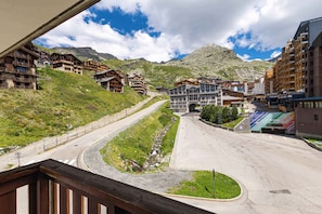 A mountain resort with multiple buildings, a winding road, and a mountain in the background. - Residence Altineige, Ski In-Out with WiFi in Val Thorens, “V10” by Versant Collection (Val Thorens)