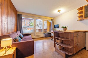 Ett mysigt vardagsrum med en soffa, en lampa och utsikt över en balkong.