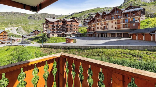 A hotel with multiple floors, balconies, and a mountainous backdrop.