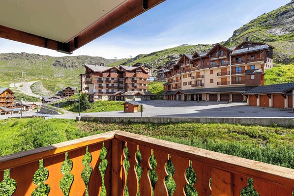 A hotel with multiple floors, balconies, and a mountainous backdrop.