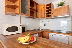 Ett kök med träskåp, en mikrovågsugn, ett handfat och en diskmaskin.