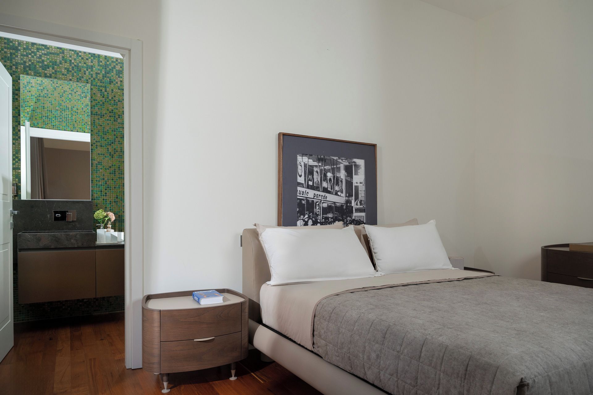 A bedroom with a bed, bedside tables, a dresser, a mirror, and a poster on the wall.