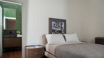 A bedroom with a bed, bedside tables, a dresser, a mirror, and a poster on the wall.