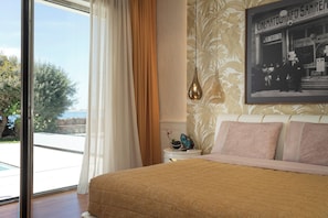 Une chambre avec un grand lit, une vue sur l’extérieur, un tableau encadré au mur et une table de chevet avec une lampe.