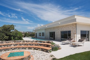 Ein modernes Haus mit Swimmingpool, Steinstufen und Außenbereich mit Sitzmöglichkeiten.
