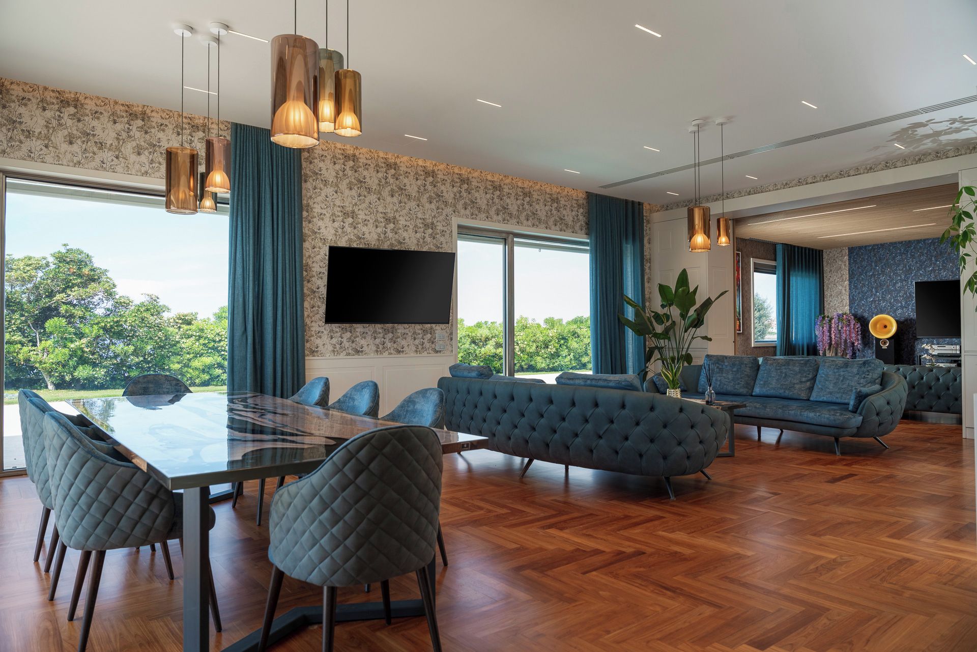 A spacious living area with a large dining table, comfortable seating, and a view of greenery.