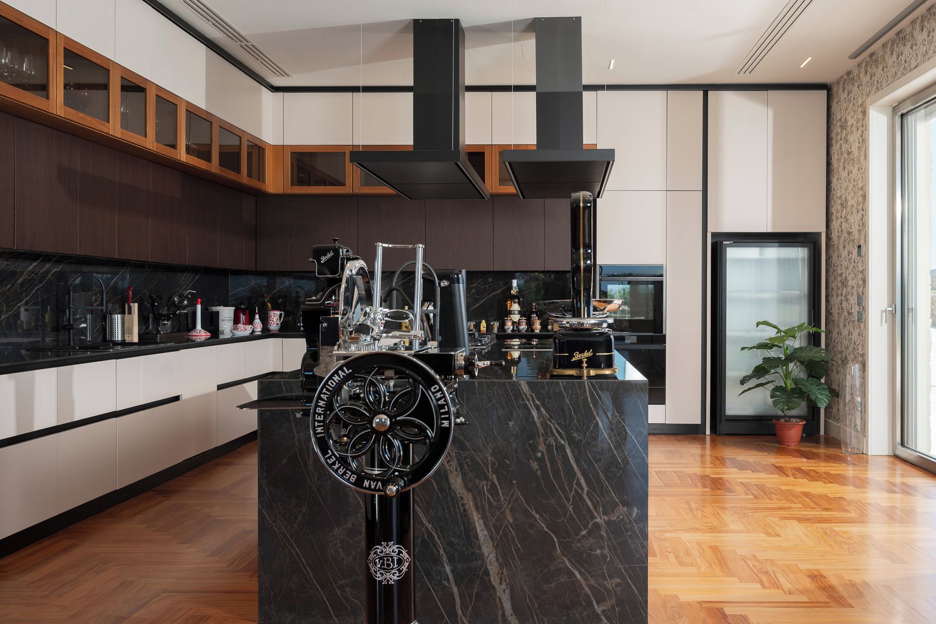 A modern kitchen with a central island, black marble countertop, and stainless steel appliances.