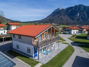A modern chalet with a red-tiled roof, a balcony, and a pool area. - Gruppenunterkunft in Inzell (Inzell)