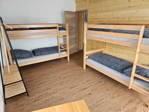 A room with two bunk beds, a wooden ladder, and a small table. - Gruppenunterkunft in Inzell (Inzell)