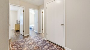 Un couloir avec un tapis à motifs, des portes blanches et un interrupteur sur le mur.