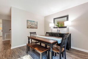 A dining area with a long table, chairs, and a mirror above. - Amazing 4-bedroom townhome (Tallahassee)
