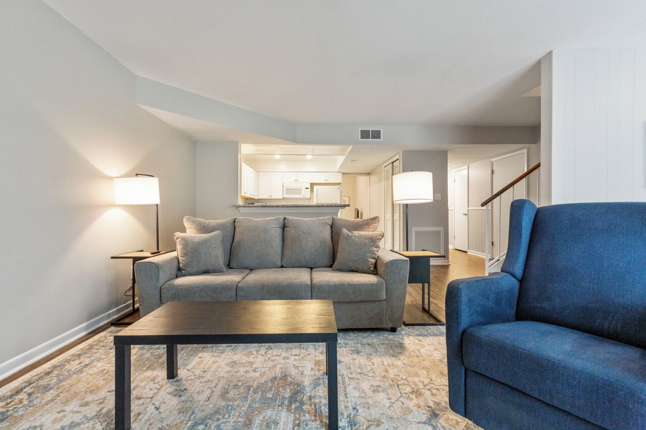A living room with a sofa, a blue armchair, a coffee table, and two floor lamps.
