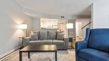 A living room with a sofa, a blue armchair, a coffee table, and two floor lamps.