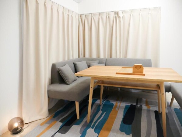 A room with a wooden table, grey sofa, and a patterned rug.