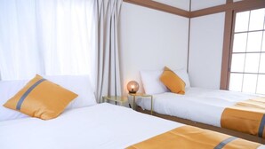 Une chambre d’hôtel avec deux lits, une table de chevet avec une lampe et une fenêtre avec des rideaux.