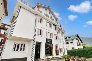 Un hotel de varios pisos con una entrada destacada, balcones y vistas claras del paisaje circundante.