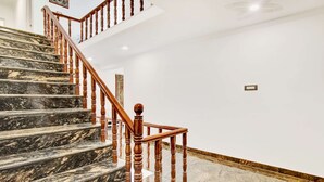 A marble staircase with wooden balusters and a handrail, leading to an upper floor. - Collection O Dal Lake (Srinagar)